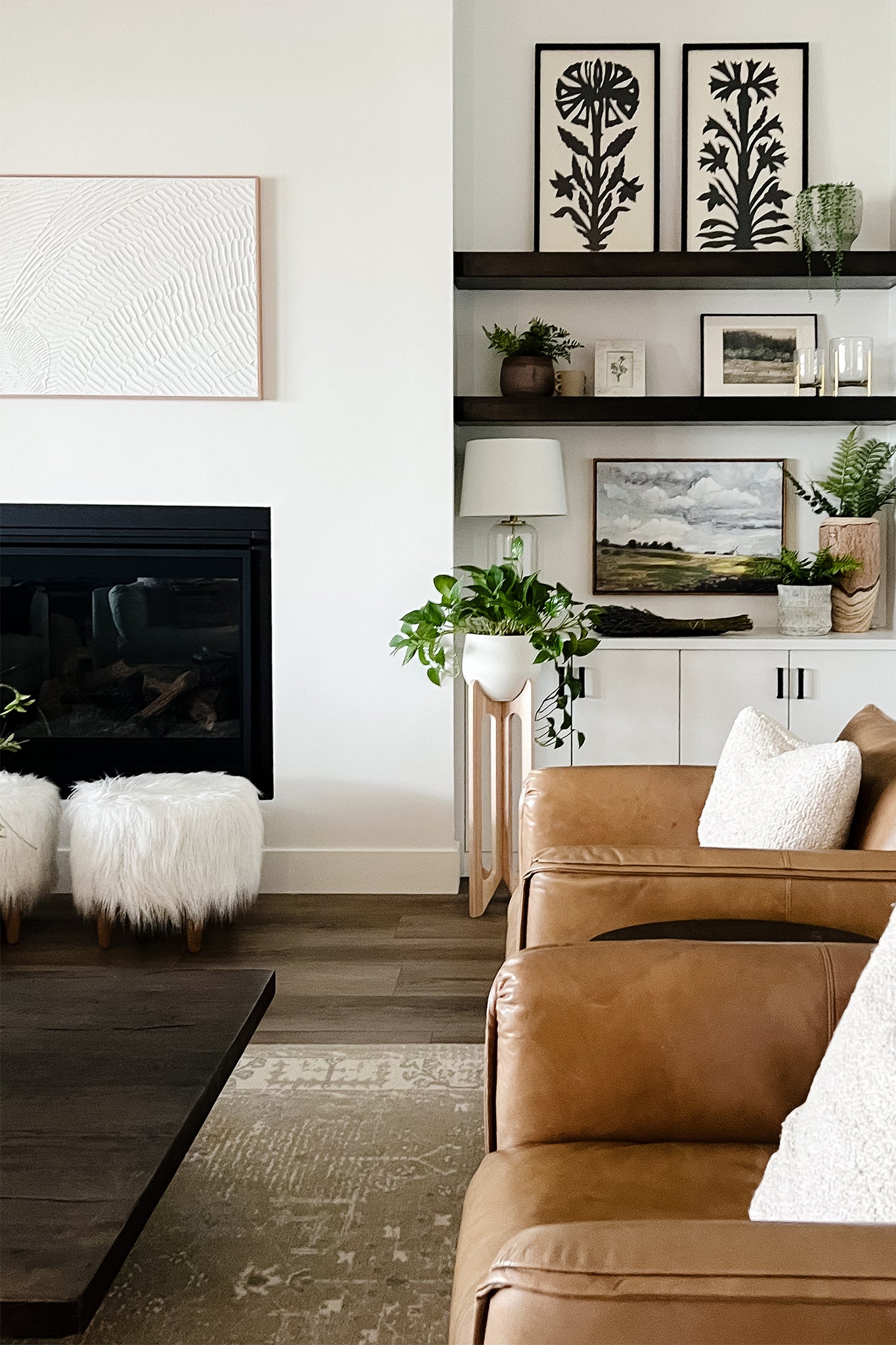 Modern living room with brown leather sofa, fireplace, and decorative elements. The Arches Plant Stand is next to the fireplace.