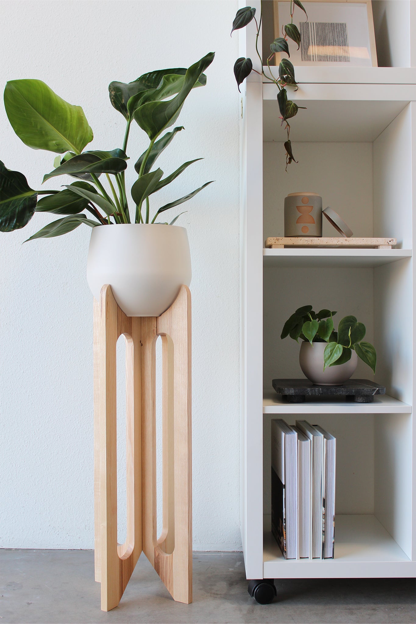 arches plant stand against white wall styled with houseplant and spun aluminum pot