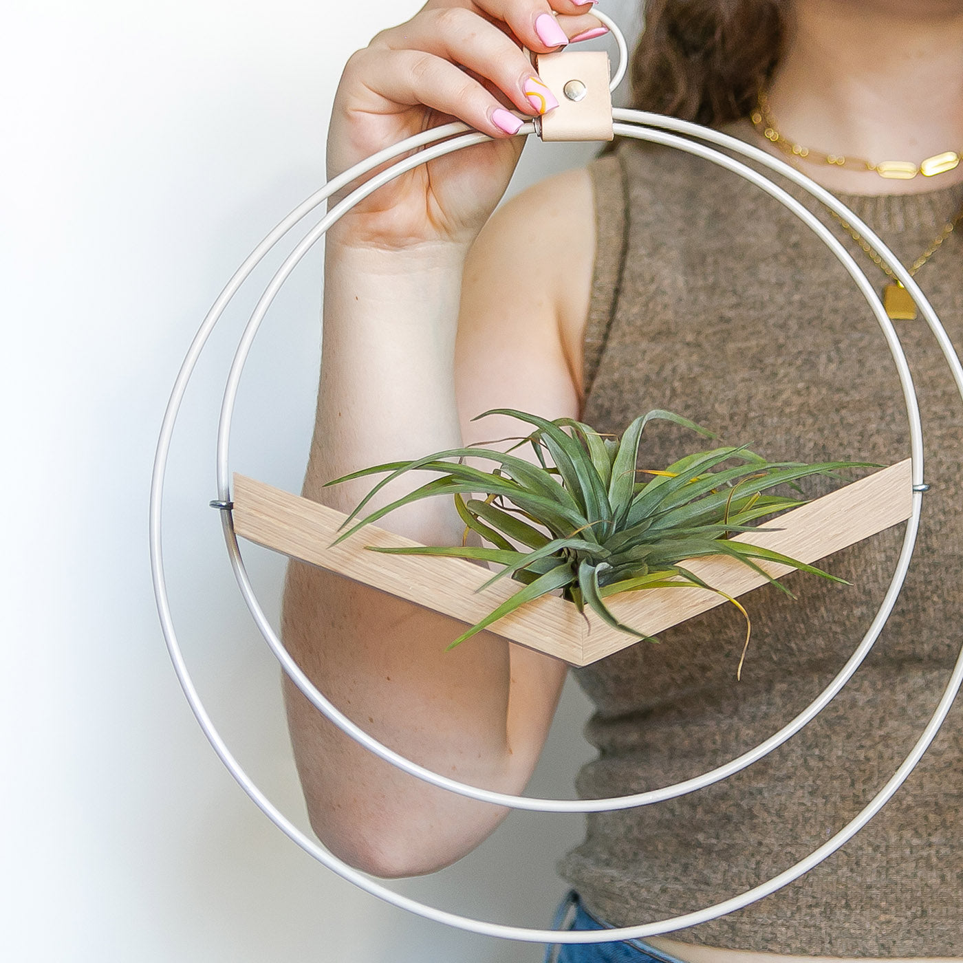 person holding large braid & wood v-hanger in white and white oak with air plant