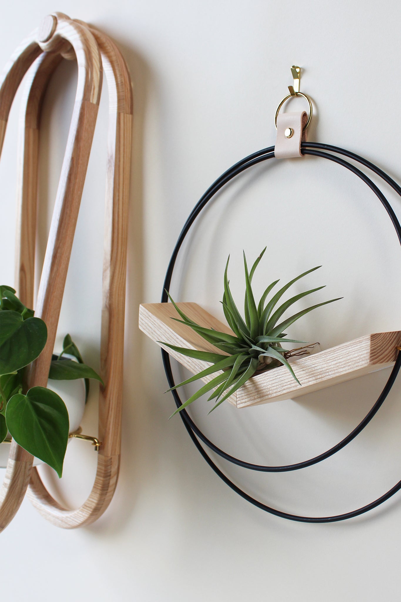 close up of mixed metal air plant holder on white wall by braid and wood
