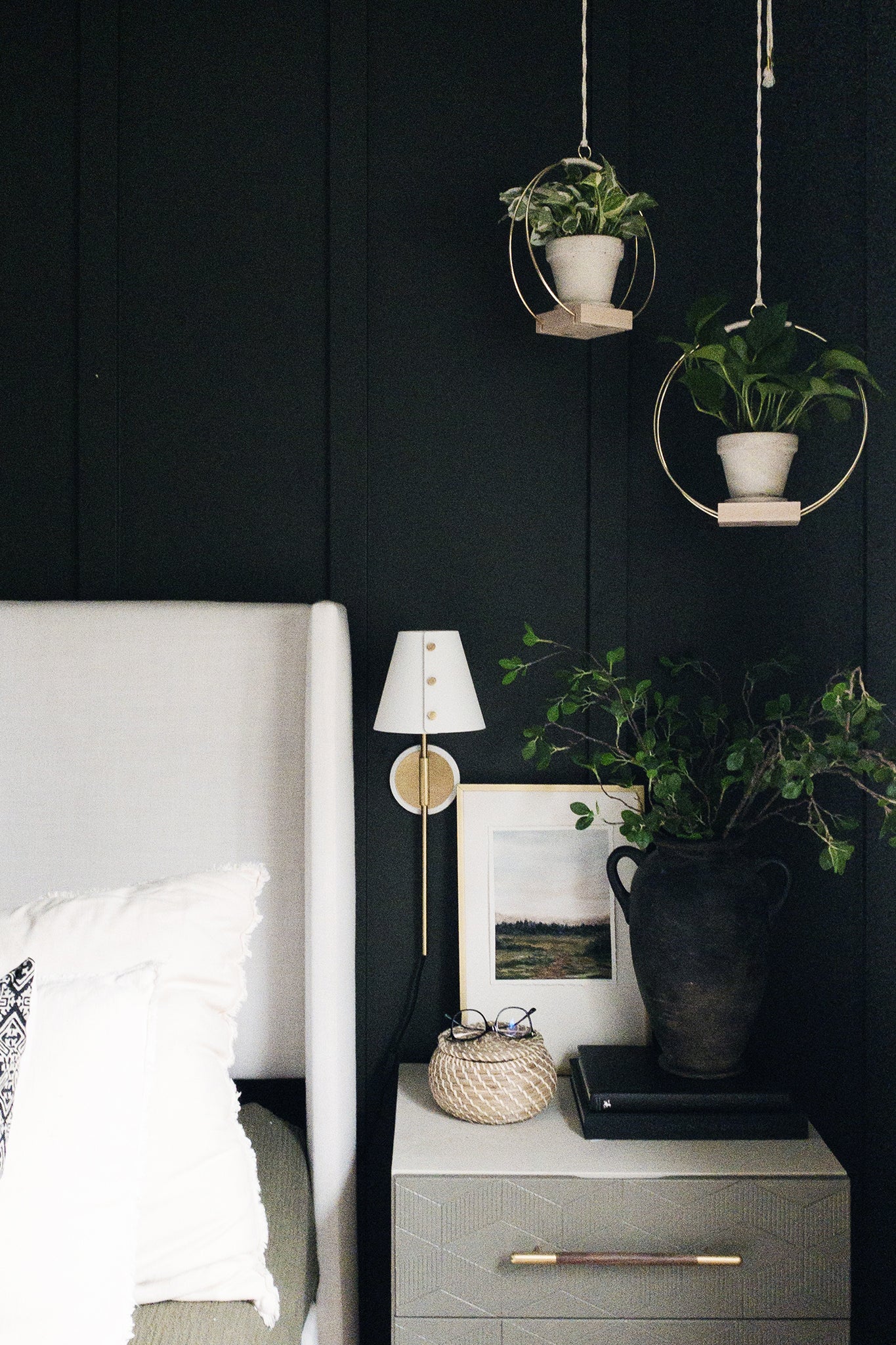two hanging planters with gold metal against a black wall backdrop