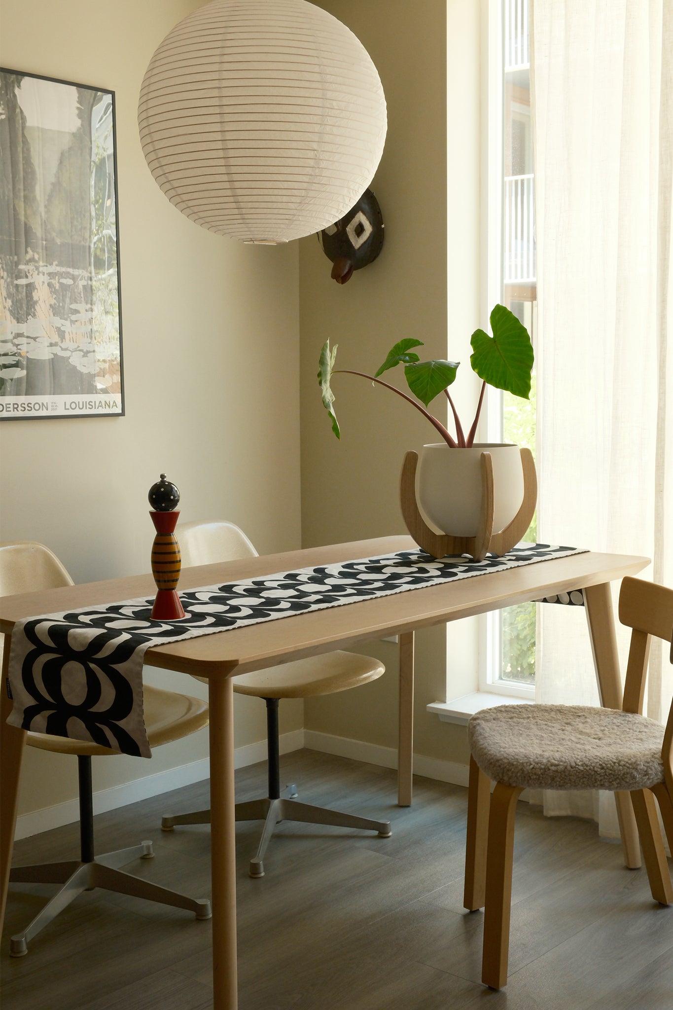 A modern dining room with a table, chairs, a paper lamp, and a Nested Plant Stand on the table.