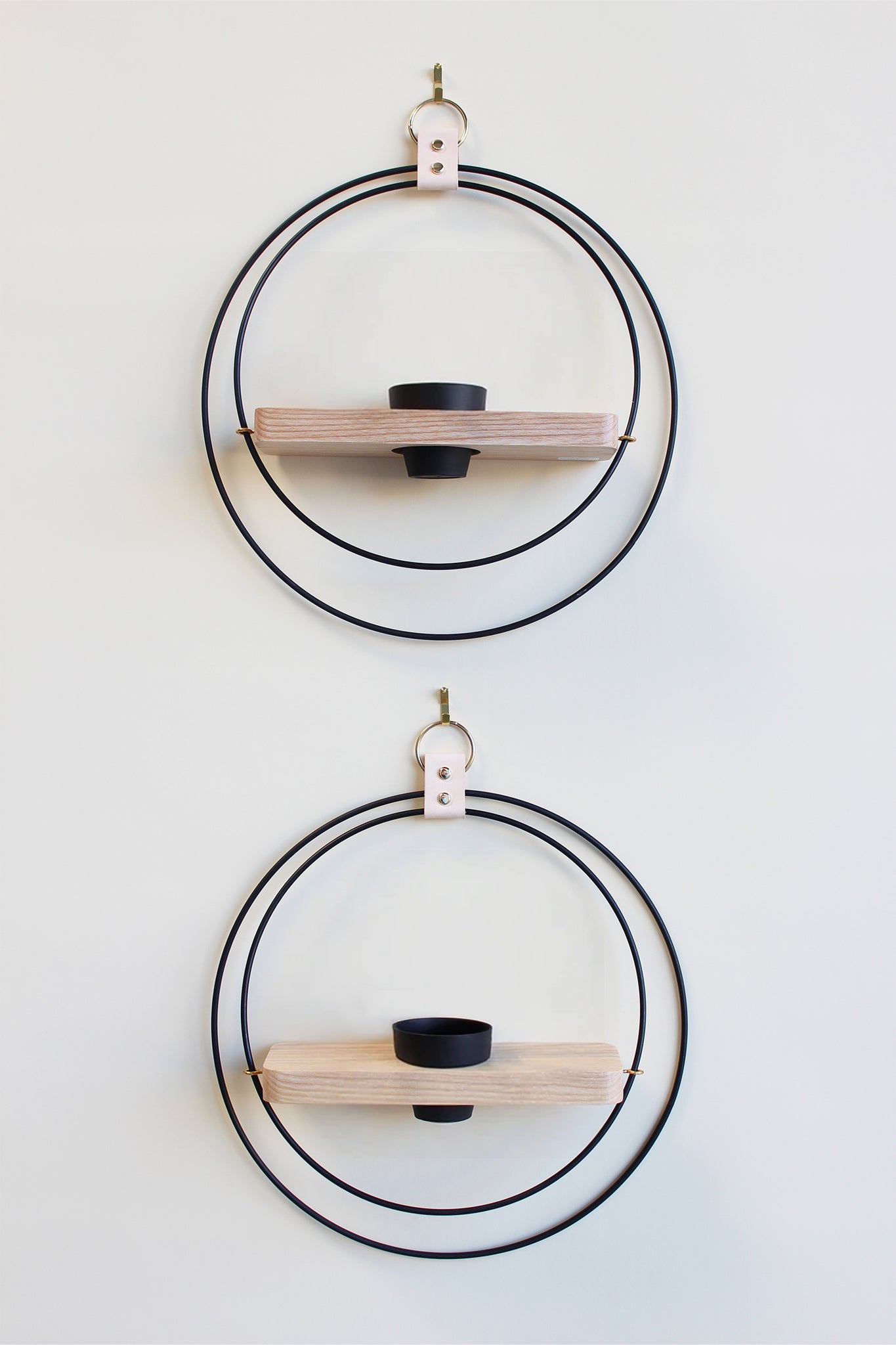 two circular wall mounted plant shelves in black metal with white ash wood and a black terracotta pot on a white background