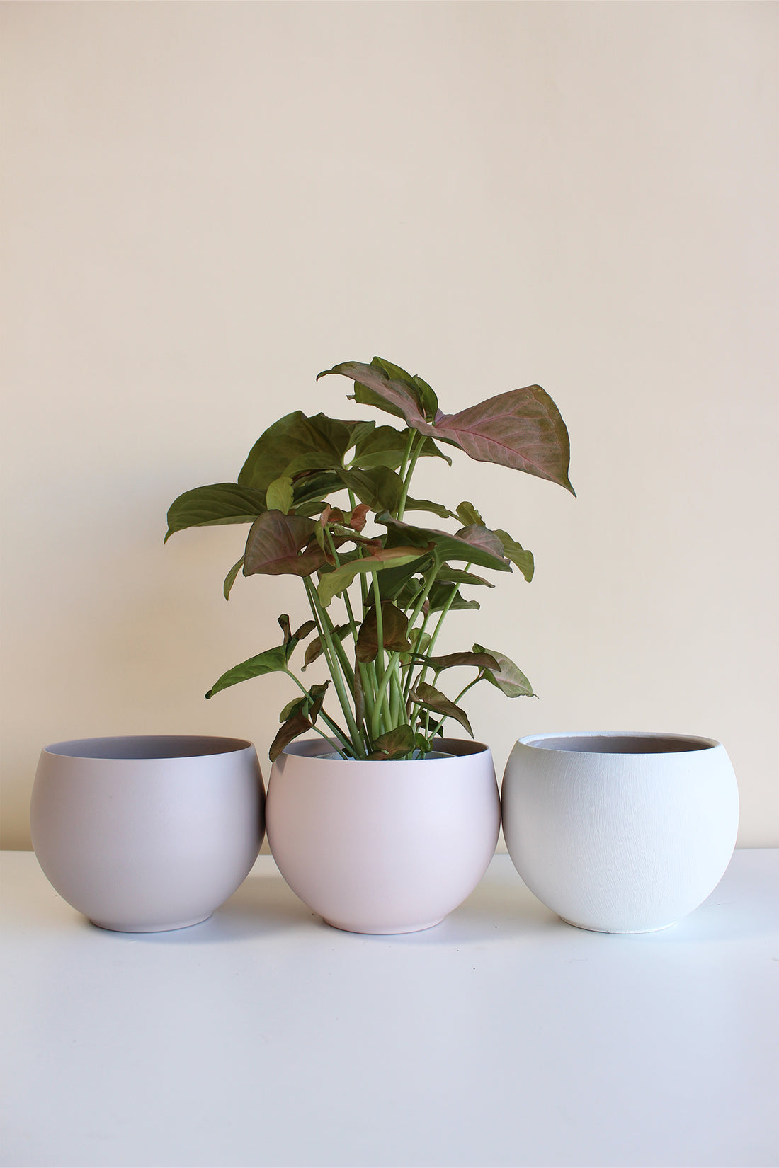 three modern spun aluminum pots in tan, blush, and white colors