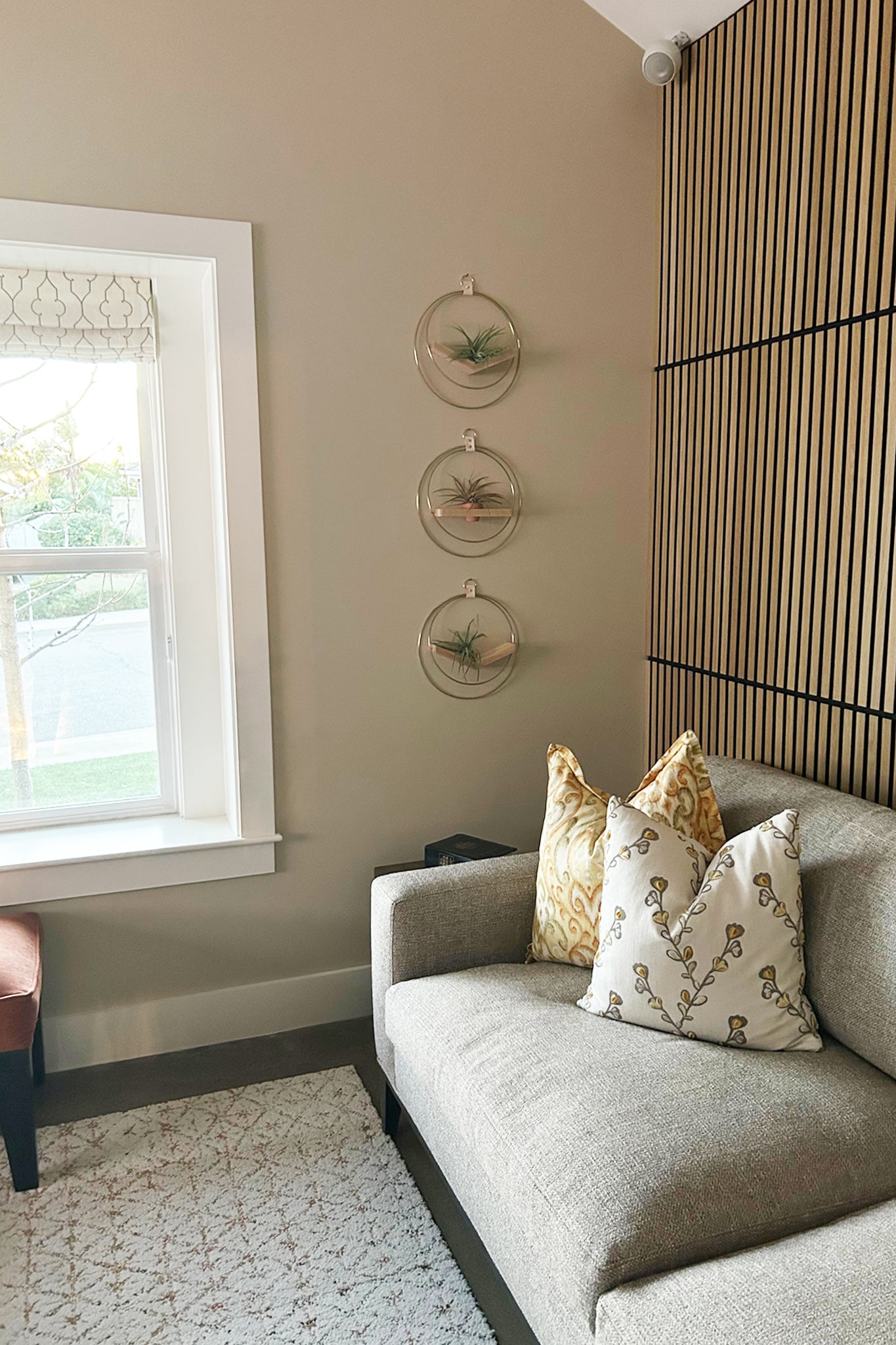 Gray sofa with decorative pillows in a room with a window, wall art, and the Mixed V-hanger and Shelf Trio on the wall.