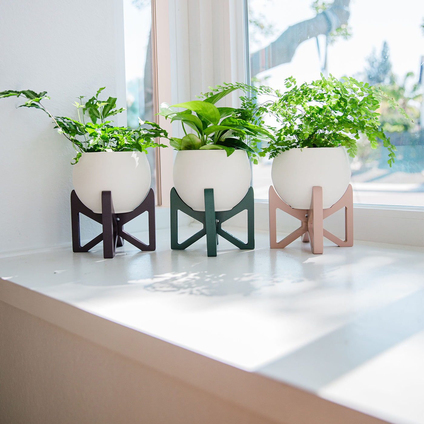 three tabletop plant stands on white window sill styled with houseplants