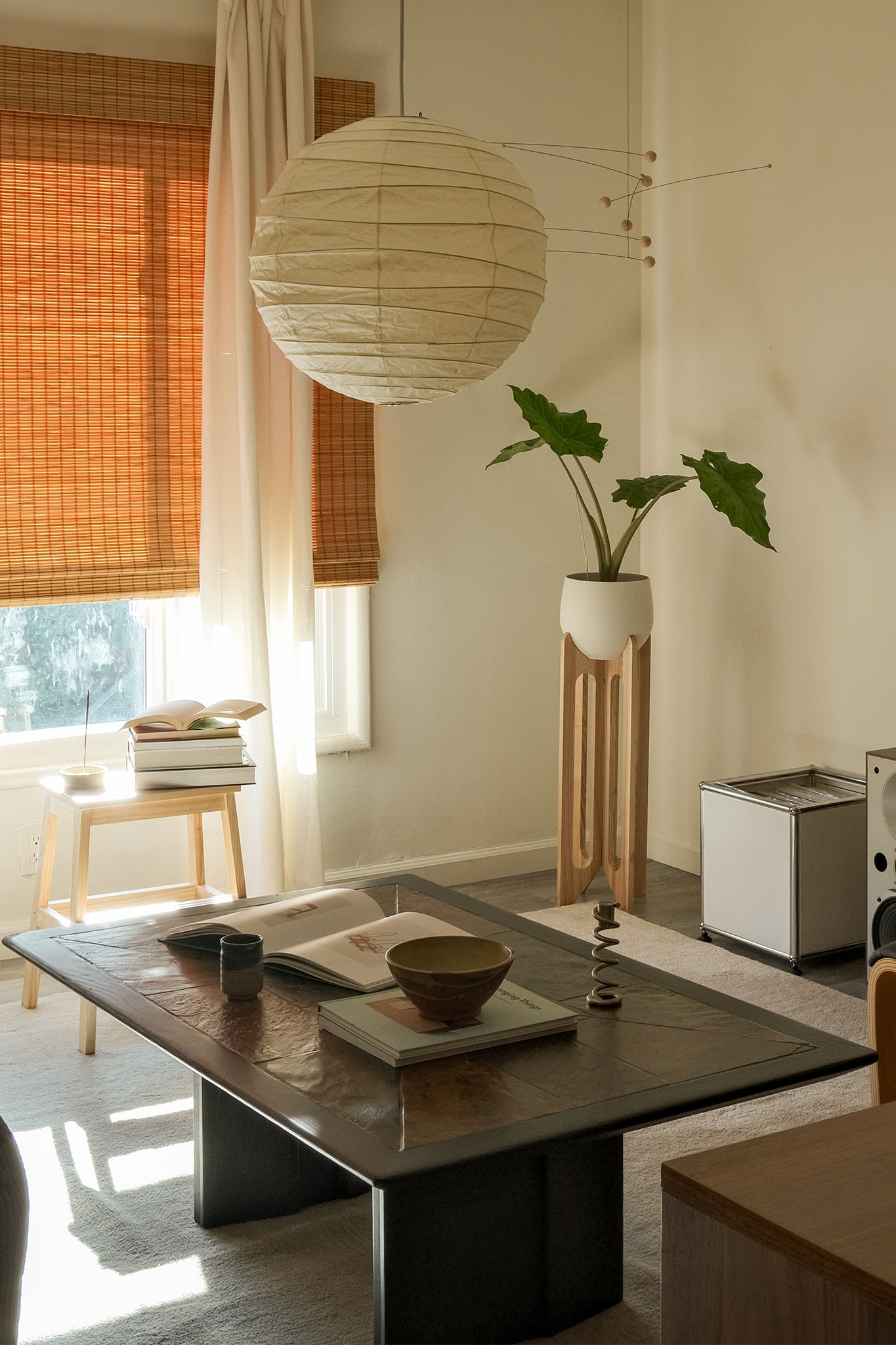 Modern living room with an Arches Plant Stand, coffee table, plant, and decorative items like coffeetable books, and ceramics.