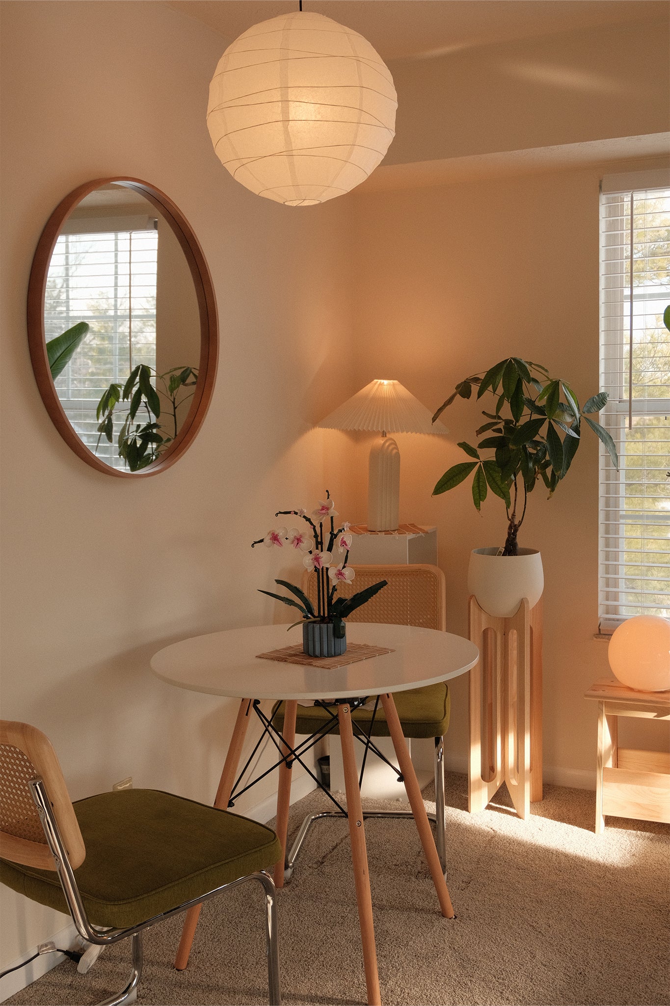 A modern dining room with round table, chairs, and the Arches Plant Stand next to the window.
