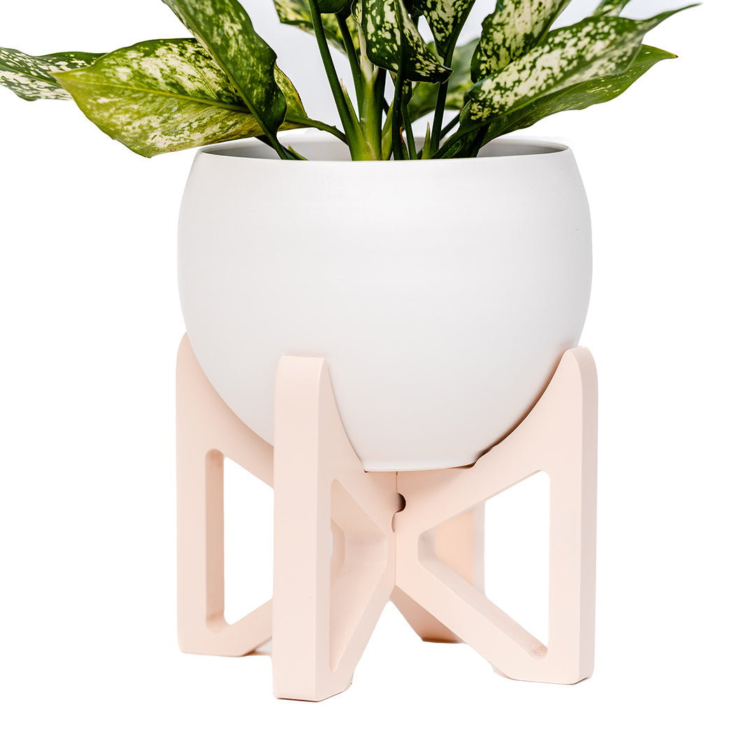blush colored wood tabletop plant stand and white aluminum pot