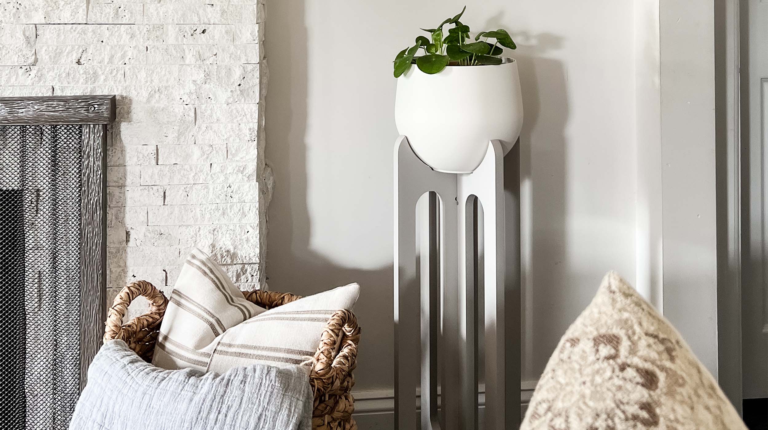 modern gray plant stand with pot by braid & wood styled next to fireplace in modern livingroom