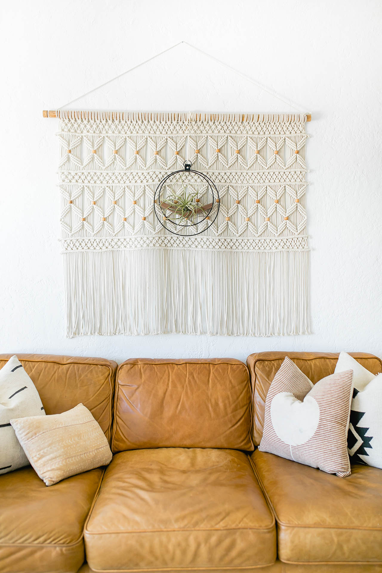 wall mounted air plant holder by braid & wood styled on macrame tapestry above tan leather couch