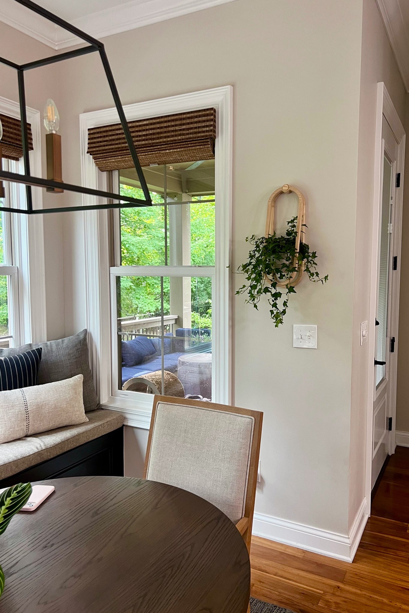 Living room with a round wooden table, cushioned bench, and wall-mounted plant.