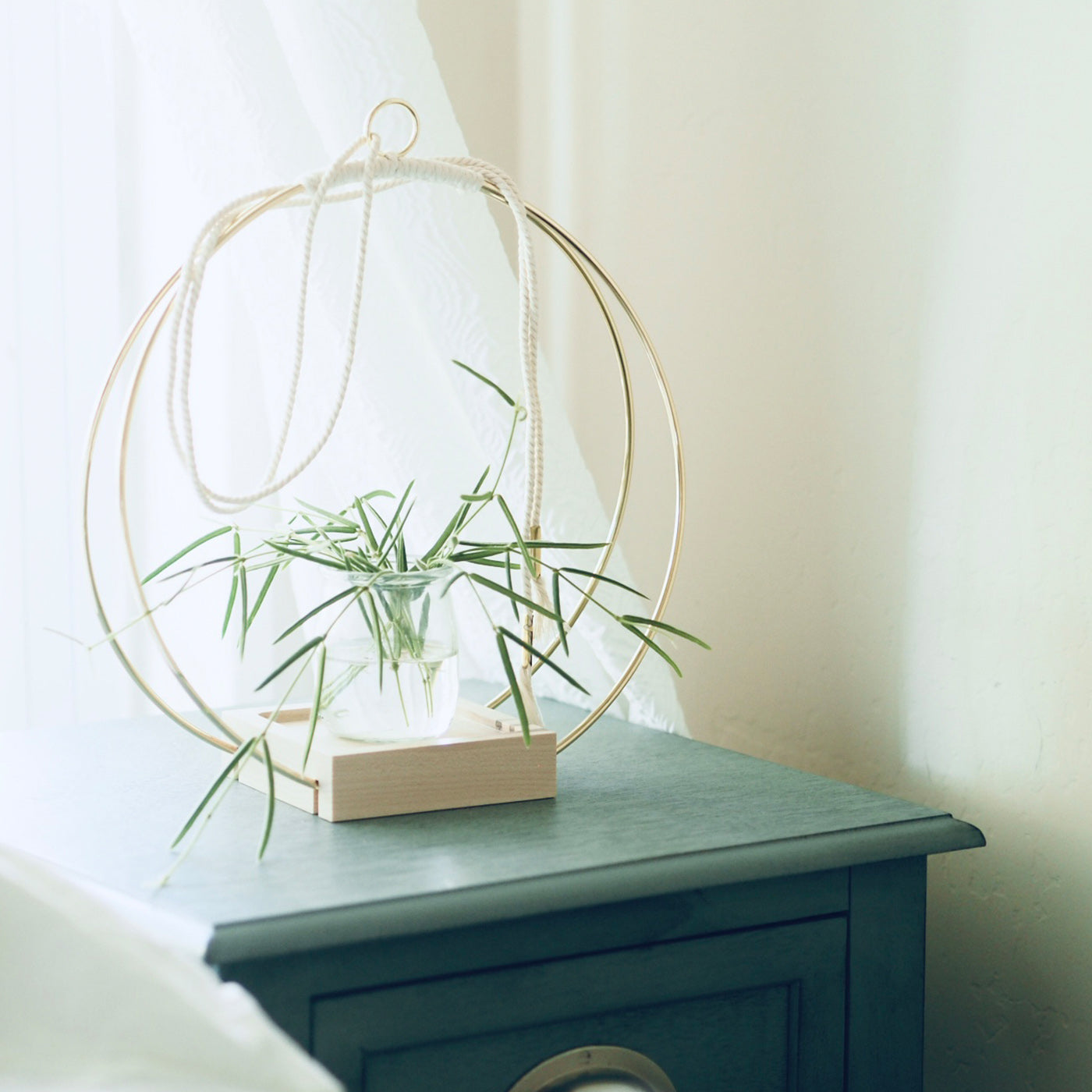 gold modern hanging planter by braid and wood sitting on teal nightstand