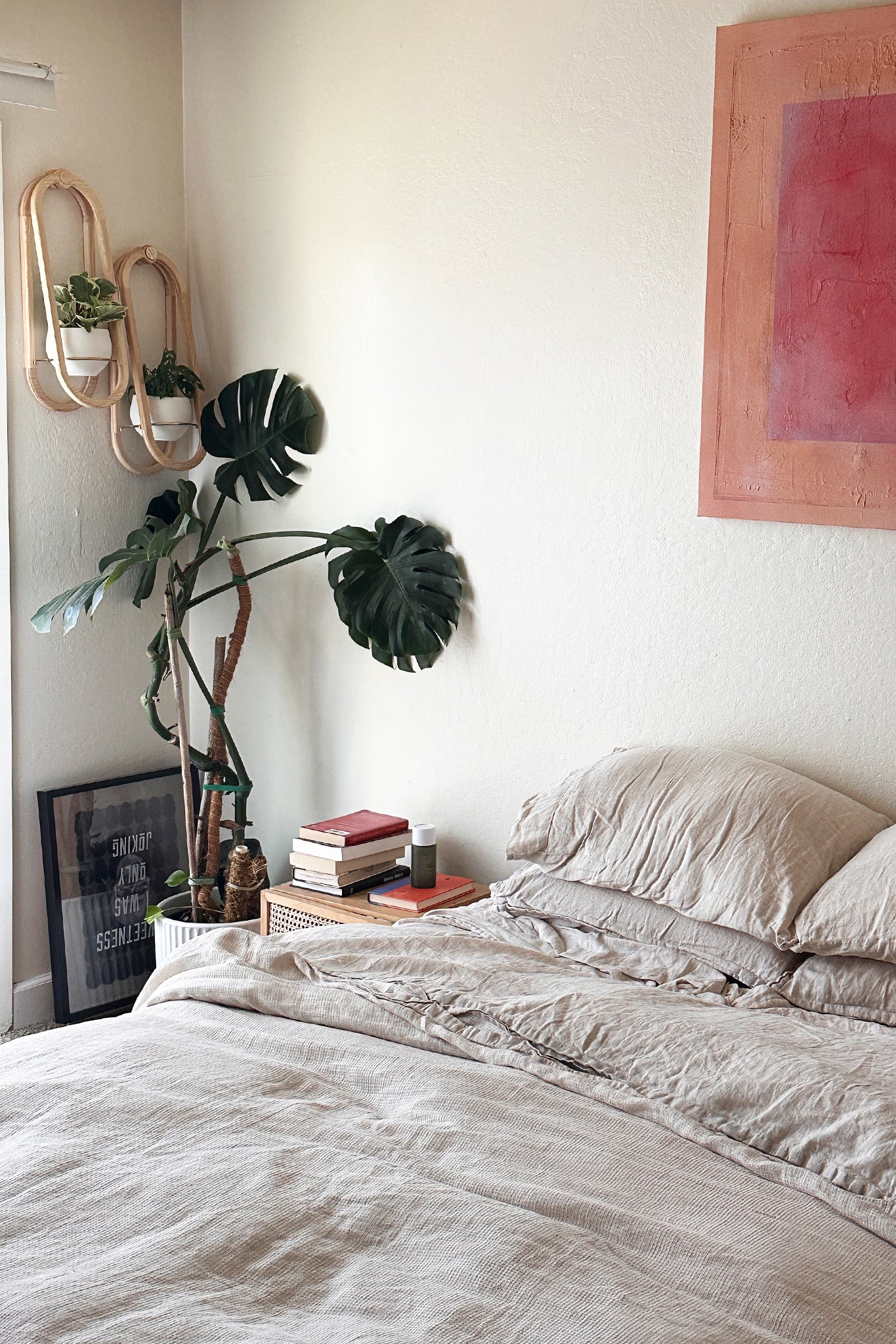 Neatly made bed in a bedroom with decorative elements including a framed art print and the Frame Wall Planter Duo on the wall.