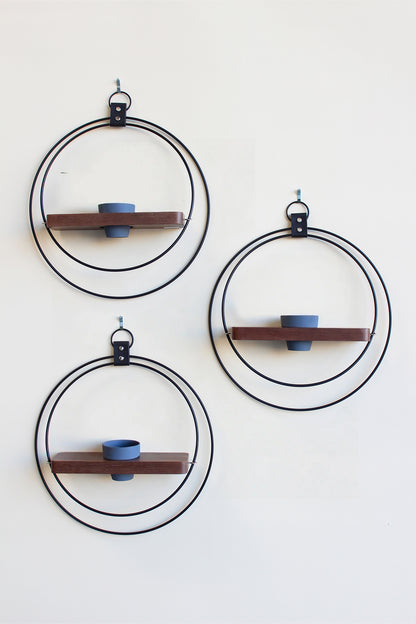 three black circular plant wall mounted plant shelves with mini charcoal pot on a white background