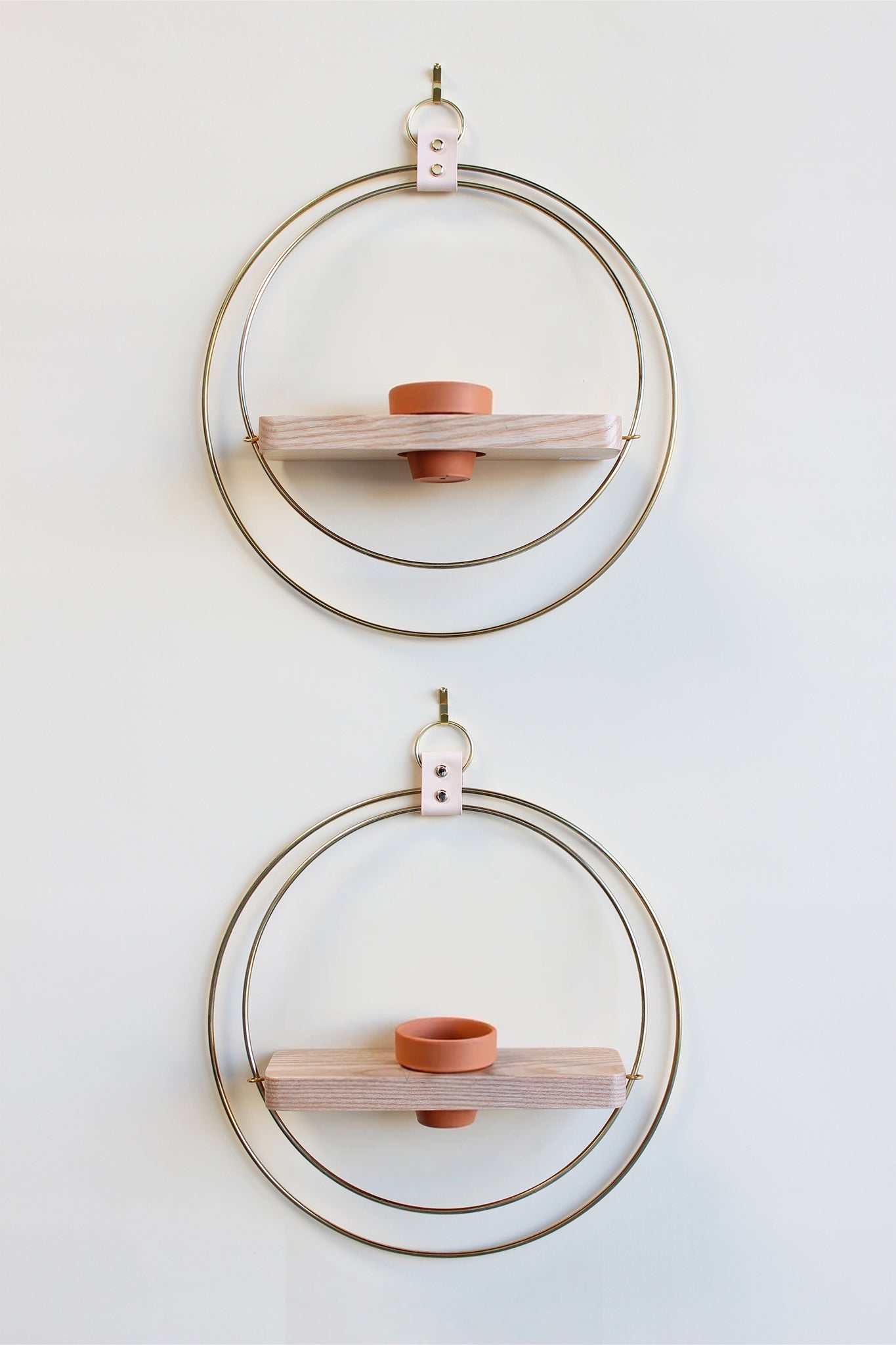 Two circular wall shelves with wooden slats and terracotta pots on a light background