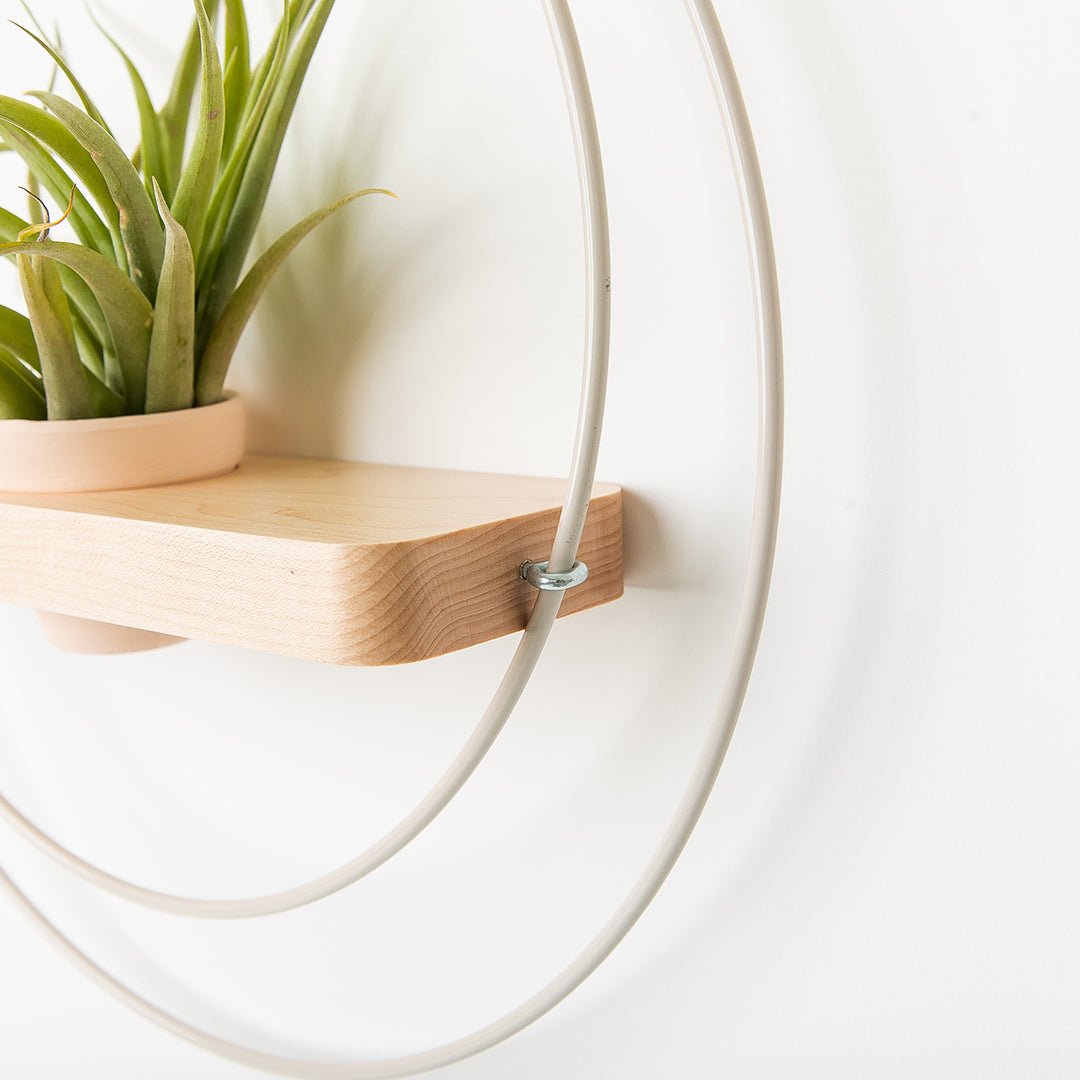 side view of plant shelf with white metal and maple wood base with blush colored pot