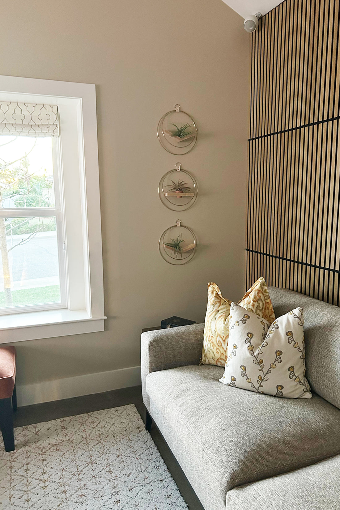 Gray sofa with decorative pillows in a room with a window, wall art, and the Mixed V-hanger and Shelf Trio on the wall.