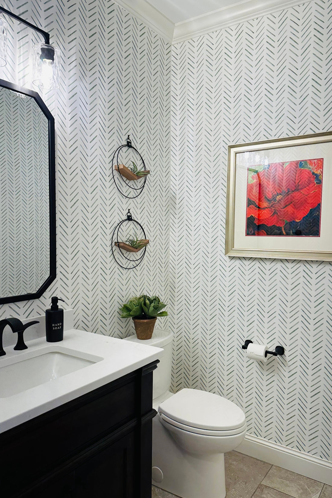 Bathroom with white chevron patterned walls, black vanity, red abstract painting, and two wall-mounted V-Hangers above the toilet