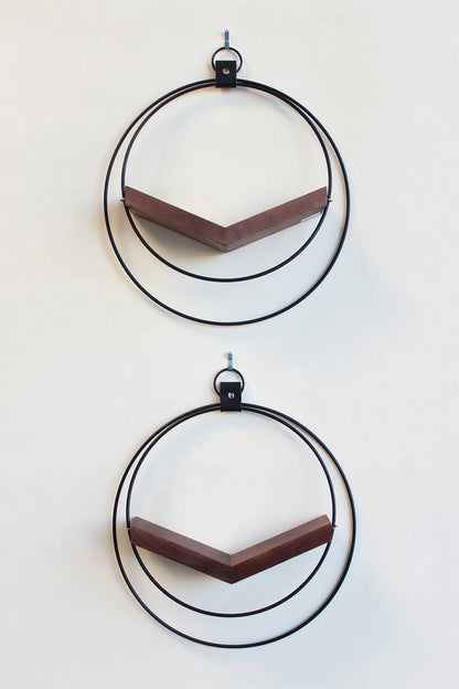 two large matte black circular modern wall mounted air plant holders with dark white ash hardwood on white background