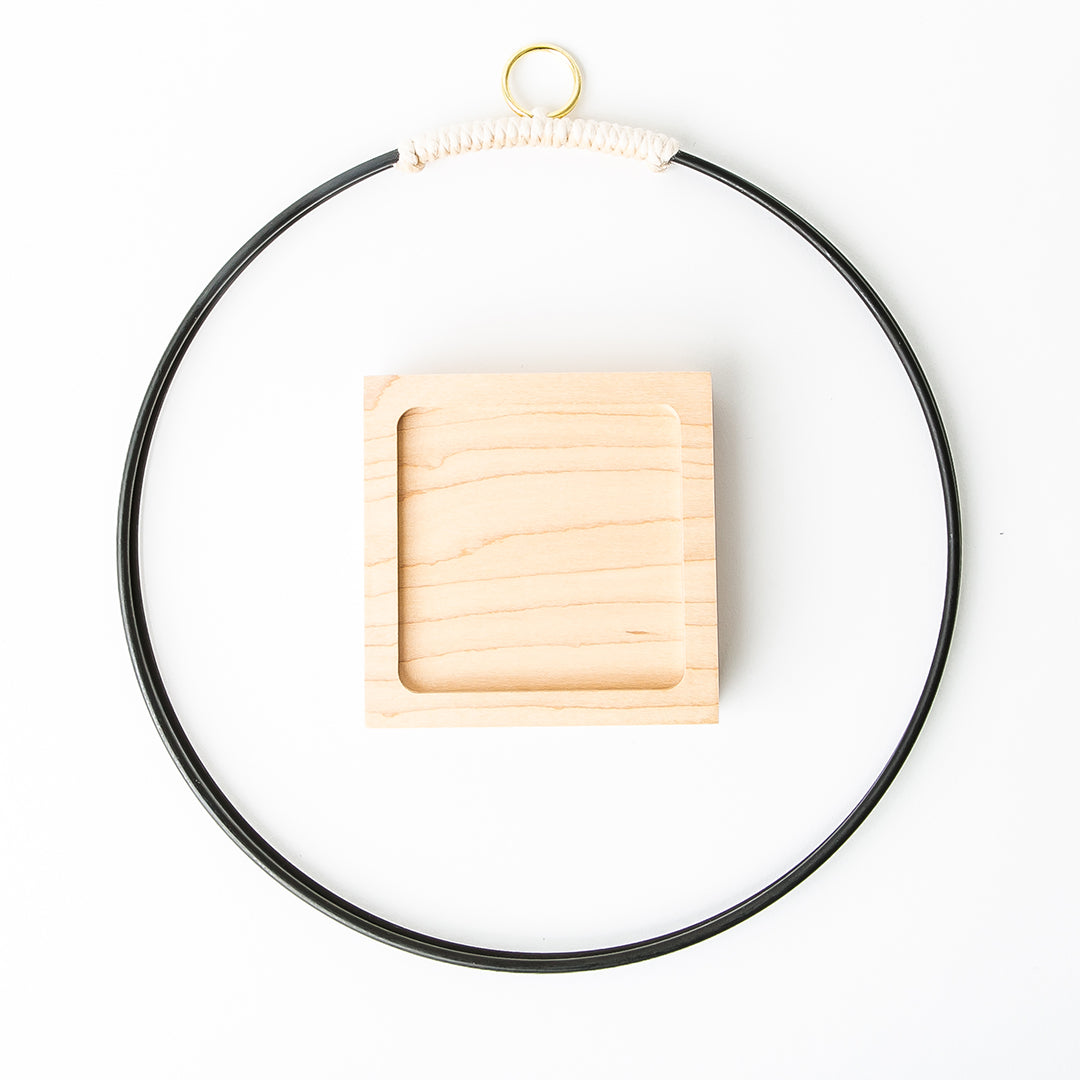 flat view of black and gold metal plant hanger with maple wood base