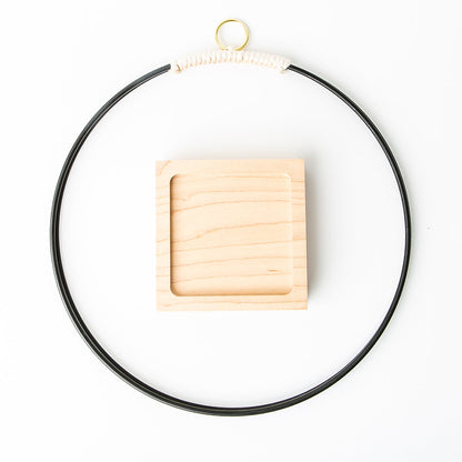 flat view of black and gold metal plant hanger with maple wood base